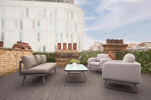 three chairs and a coffee table on a balcony at Be London - The Chinatown Residences in London