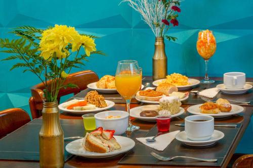 a table topped with plates of food and orange juice at Hotel Laghetto Viale in Gramado