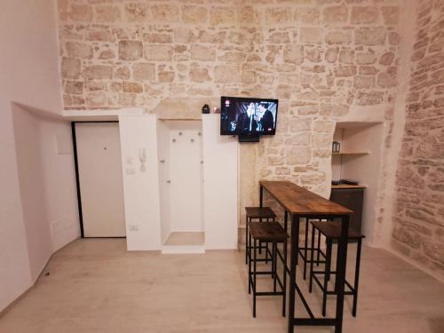 a room with a table and chairs and a tv on the wall at Maison Divino in Trani