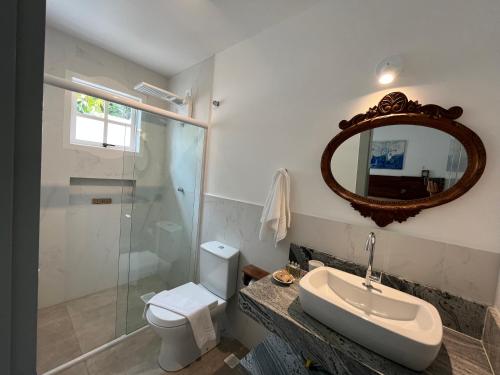 a bathroom with a toilet and a sink and a mirror at Casa Arte Cabore in Paraty