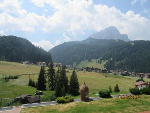 a green field with a mountain in the background at Garni La Majon in Selva di Val Gardena