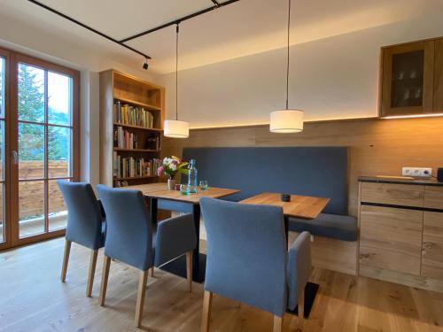 a kitchen with a dining room table and blue chairs at Oberleiten Apartments in Wagrain