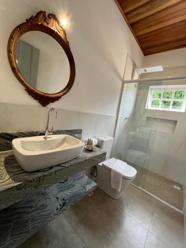 a bathroom with a sink and a toilet and a mirror at Casa Arte Cabore in Paraty
