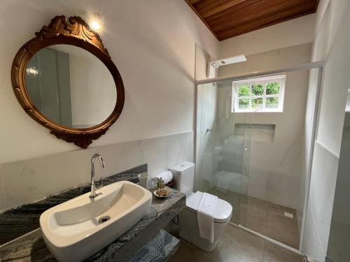 a bathroom with a sink and a mirror and a toilet at Casa Arte Cabore in Paraty