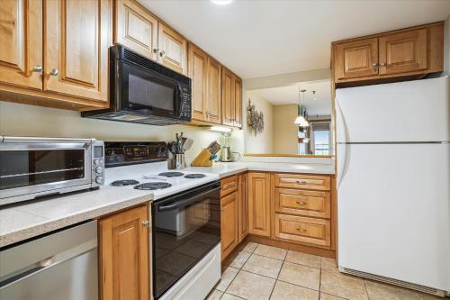 a kitchen with wooden cabinets and a white refrigerator at Highridge B14 Enjoy the view ski back trail shuttle service sports center in Killington