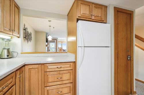 a kitchen with a white refrigerator and wooden cabinets at Highridge B14 Enjoy the view ski back trail shuttle service sports center in Killington