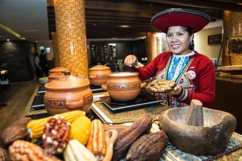 Kobieta stoi przed stołem z jedzeniem w obiekcie Sonesta Hotel Cusco w Cuzco