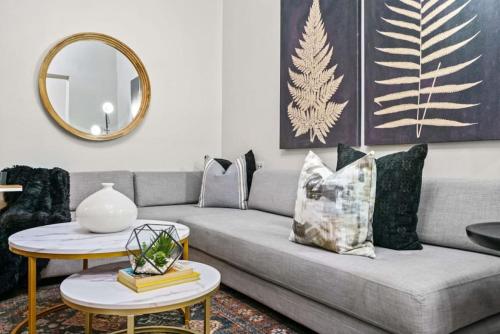 a living room with a gray couch and a gold mirror at 3BR Retreat Walkable to Columbia University in New York