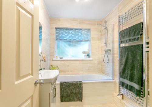 ein Bad mit einer Badewanne, einem Waschbecken und einer Dusche in der Unterkunft Drum Cottage in Appledore