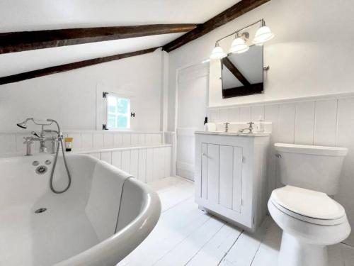 baño blanco con bañera y aseo en Historic Estate - 5 min to Mohawk Mt Ski Resort, 