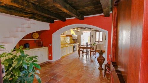 a kitchen with red walls and a dining room with a table at Casa Clara in Mamoiada