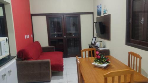a living room with a red couch and a table at Paraíso tropical in Balneário Gaivotas