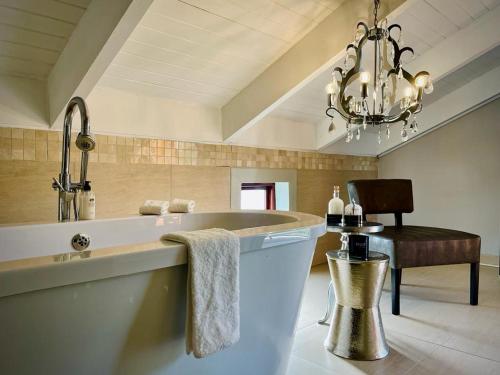 a large bathroom with a tub and a chandelier at Calais Guest House in Franschhoek