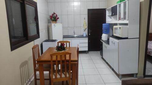 a small kitchen with a wooden table and chairs at Paraíso tropical in Balneário Gaivotas