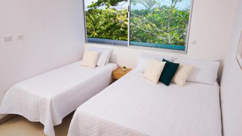 twee bedden in een kamer met twee ramen bij Magico Apartamento Frente al Mar 4 Habitaciones PAZ335 in Coveñas