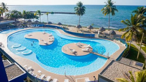 een uitzicht op een zwembad met stoelen en de oceaan bij Magico Apartamento Frente al Mar 4 Habitaciones PAZ335 in Coveñas