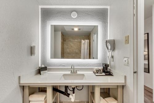 a white bathroom with a sink and a mirror at Suburban Studios Salt Lake City Airport in Salt Lake City
