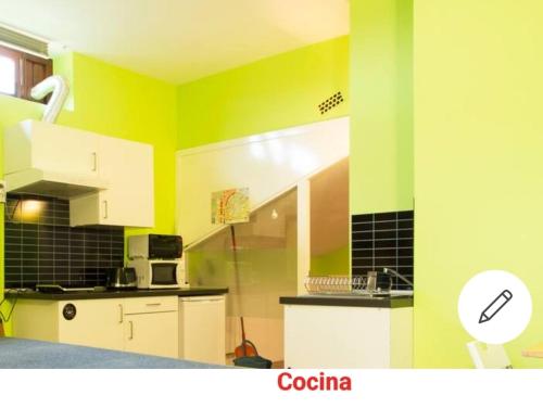 una cocina con paredes verdes y amarillas y armarios blancos en Loft cerca de la playa, en Sopelana