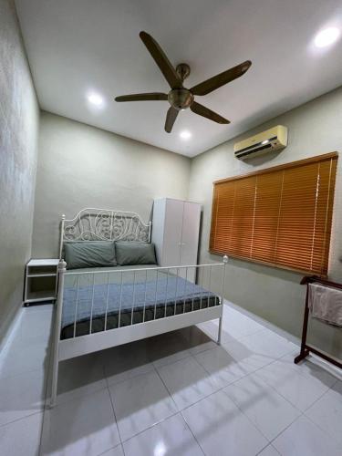 Cama en habitación con ventilador de techo en Teratak LS Homestay, en Kubang Semang