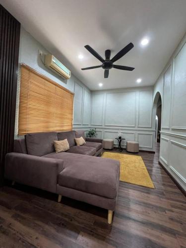 een woonkamer met een bank en een plafondventilator bij Teratak LS Homestay in Kubang Semang