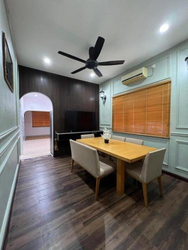 a dining room with a wooden table and a ceiling fan at Teratak LS Homestay in Kubang Semang