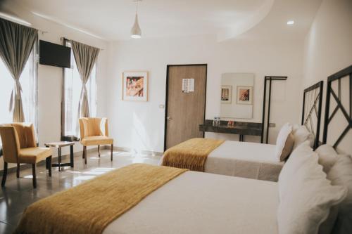 Cette chambre comprend deux lits, un bureau et des chaises. dans l'établissement MCI HOTEL, à San Juan de los Lagos
