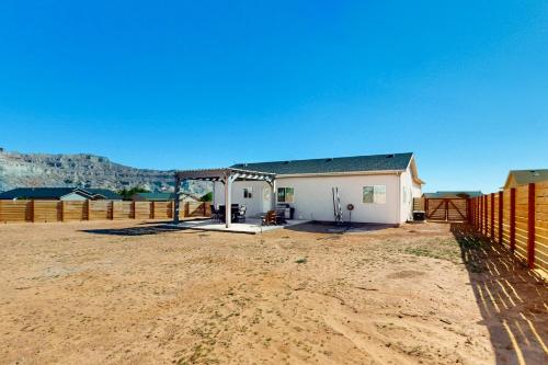 a white house with a fence in a field at Red Rock Retreat in Big Water