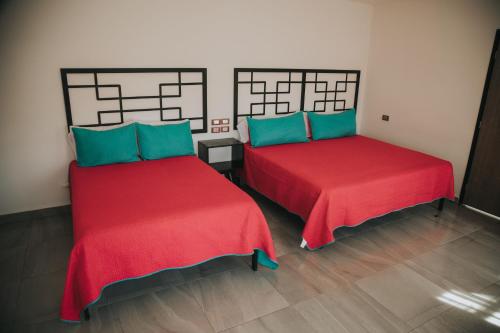 two beds in a room with red and blue at MCI HOTEL in San Juan de los Lagos