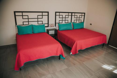 two beds in a room with red and blue at MCI HOTEL in San Juan de los Lagos