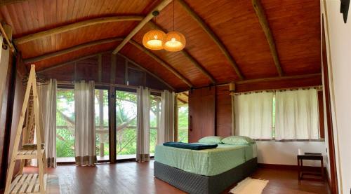 a bedroom with a bed in a room with windows at FLORA Praia do Sono Lodge & Trekking in Paraty