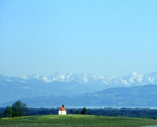 a house in a field with mountains in the background at Hotel Gerbe in Friedrichshafen