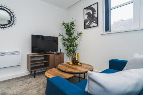 a living room with a blue couch and a tv at VICHY - The Thornhill Delux Apartments in Wakefield