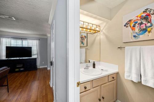 a bathroom with a sink and a television in it at Montrose 2BR Sleeps 10 Walkable Gated Parking in Houston