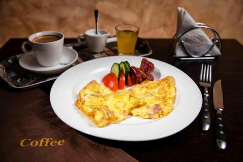 a white plate with an omelet and fruit on a table at Adac Boutique Hotel in Bucharest