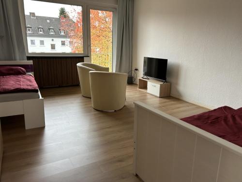 a living room with two chairs and a television at Central Service Apartment in Recklinghausen