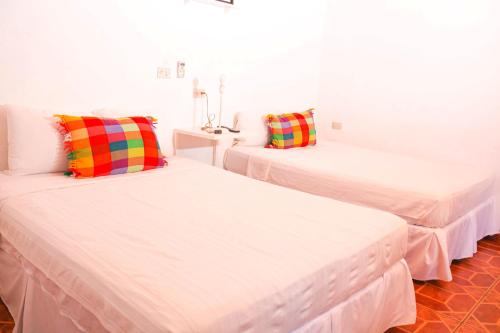 Duas camas num quarto com paredes brancas em La Casa de Mamapán Hotel Colonial Ahuachapan em Ahuachapán