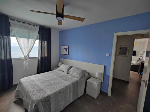 Faro de Cullera I في فارو دي كوييرا: غرفة نوم زرقاء مع سرير ومروحة سقف