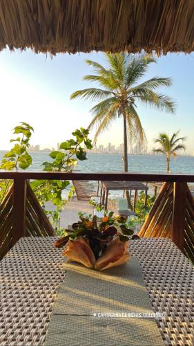 a table on a balcony with a palm tree and the ocean at Namaste Beach Club & Hotel in Tierra Bomba