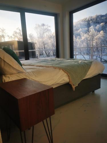 a bed in a room with large windows at Aurora View Lapland, Sky View Bedroom & Jacuzzi in Kilpisjärvi