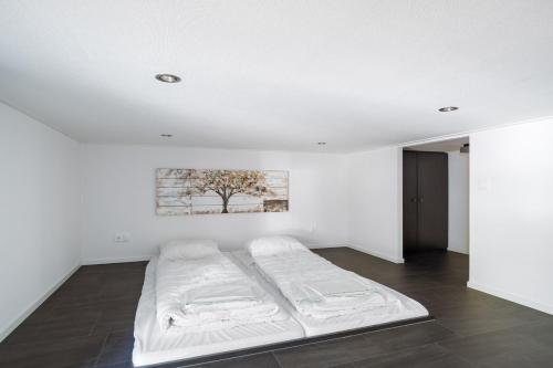 een witte kamer met een bed en een schilderij aan de muur bij Holiday Home Maridu Forest Cube in Arnhem
