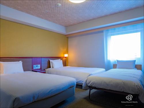 那覇市にあるダイワロイネットホテル那覇国際通りのベッド2台と窓が備わるホテルルームです。