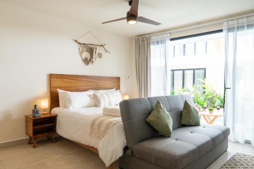 - une chambre avec un lit, un canapé et une fenêtre dans l'établissement Santal Tulum, à Tulum