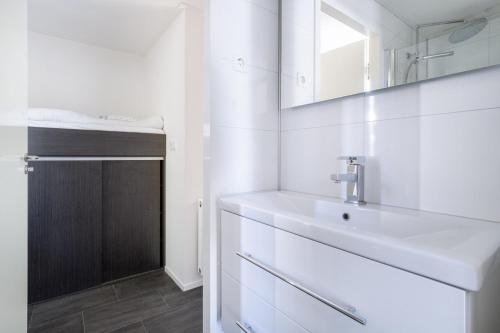 een witte badkamer met een wastafel en een spiegel bij Holiday Home Maridu Family L-Cube in Arnhem