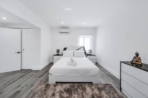 een witte slaapkamer met een wit bed en een tapijt bij Homey Studio near the Airport and Water Park in Miami