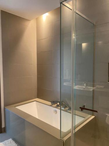 y baño con ducha de cristal y bañera. en Modern 2BR and maid room with big terrace city walk en Dubái