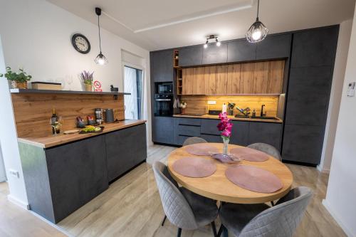 a kitchen and dining room with a wooden table and chairs at Apartman Nebo - Pogled na Stari Grad i Minizoo besplatne ulaznice - Free tickets in Ðurđevac