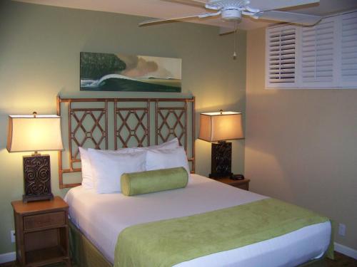 a bedroom with a bed with two lamps and a fan at Sea Village in Kailua-Kona