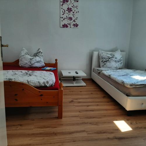 Habitación con 2 camas individuales y suelo de madera. en Ferienhaus Hostel Zimmer Appartment in Thüringen en Schwallungen
