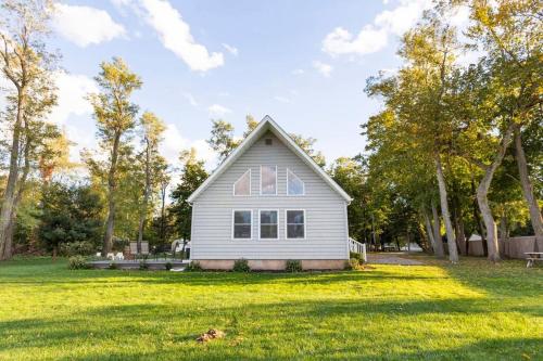 ein weißes Haus auf einem Rasenplatz mit Bäumen in der Unterkunft Bright Oasis in Beautiful North Fork Wine Country in Southold