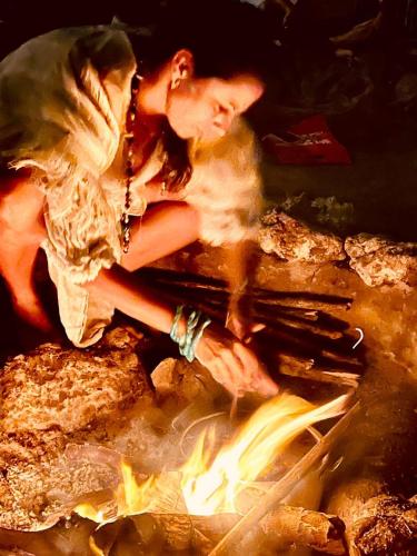 a woman is standing over a camp fire at Namaste Beach Club & Hotel in Tierra Bomba